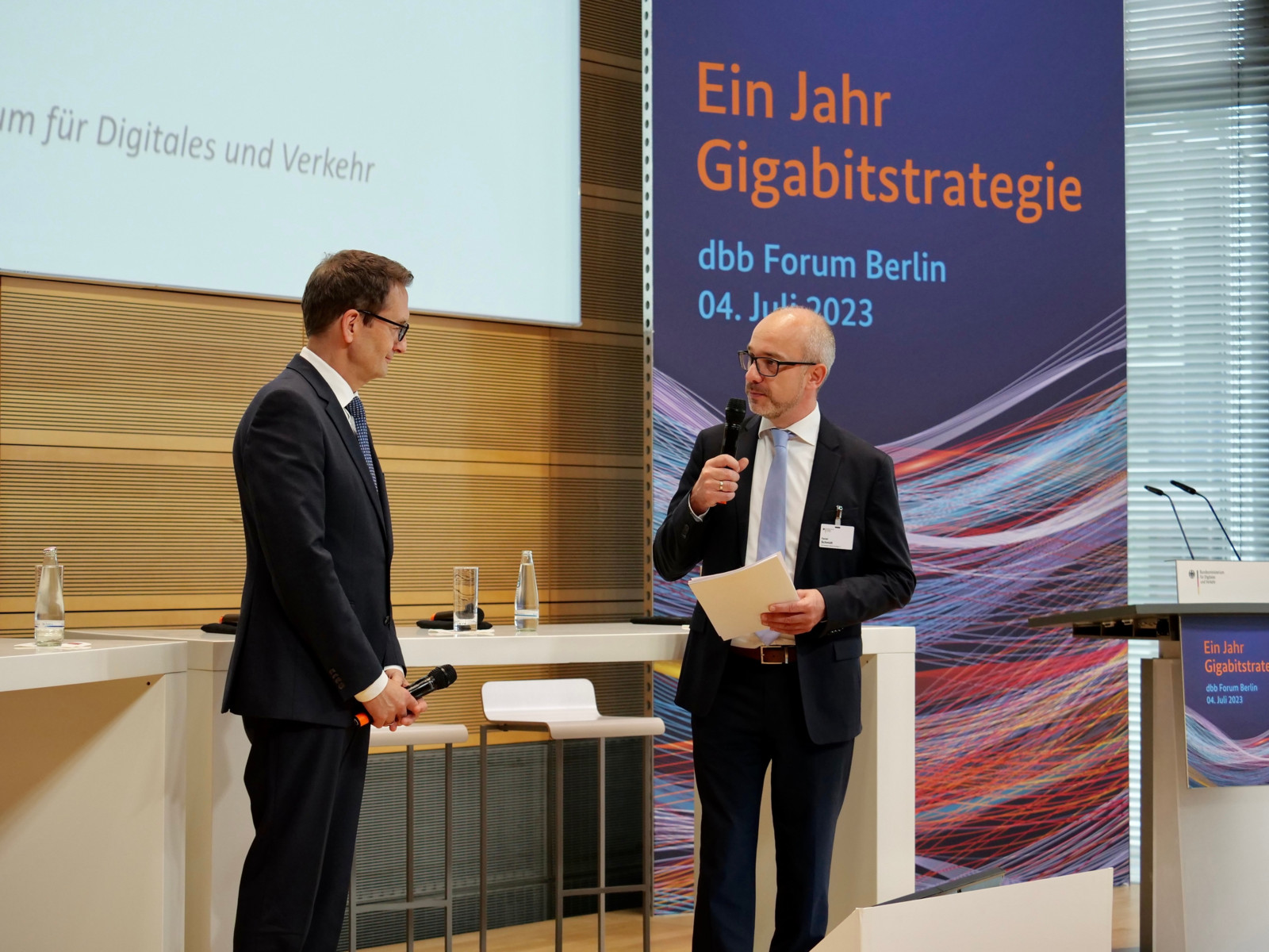 Daniel Schmidt, DIN-Vorstand überreicht  ein Exemplar der DIN 18220 an Stefan Schnorr, Staatssekretär im Bundesministerium für Digitales und Verkehr.